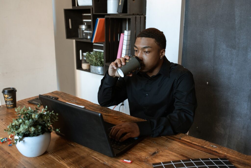 PontoTel Man in Black Long Sleeves Drinking Cup of Coffee while Busy Looking at the Screen of Laptop