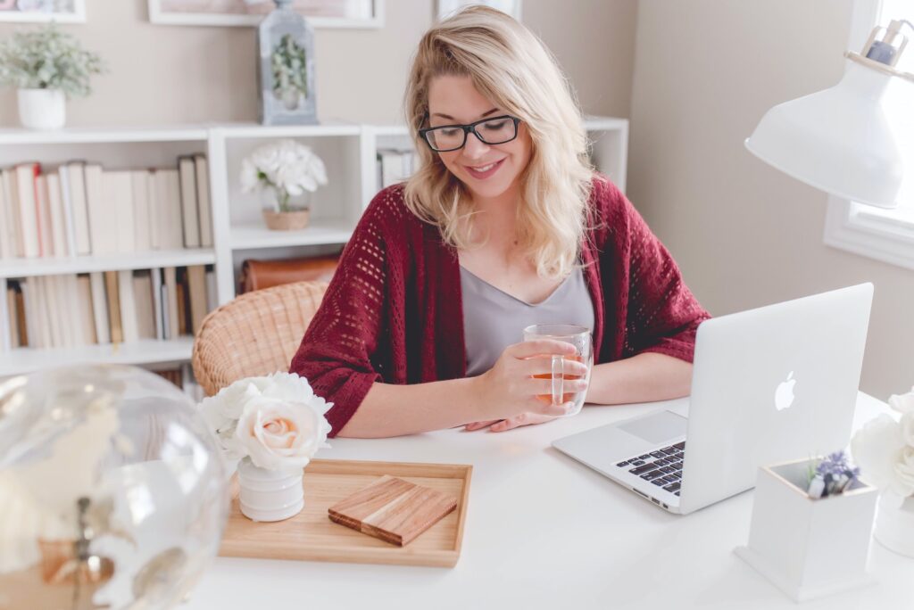 DBServices woman smiling holding glass mug sitting beside table with MacBook