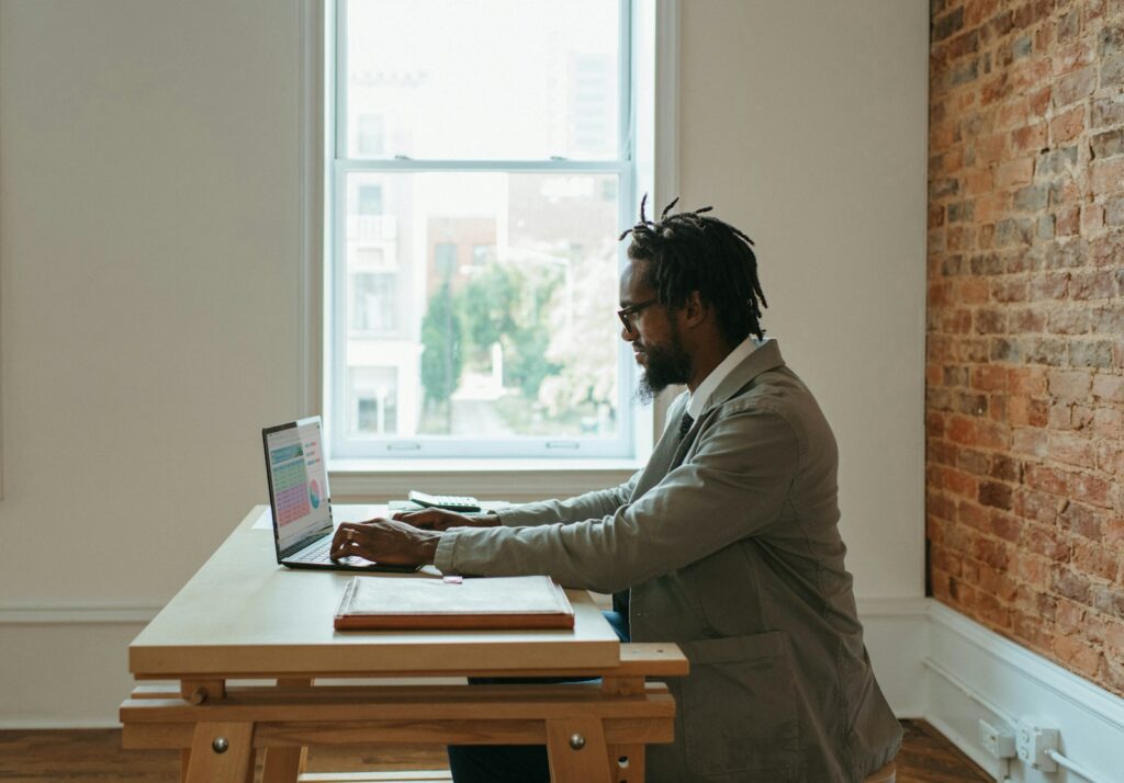 64 Vagas de Emprego na Stefanini, Híbridas e Presenciais a person sitting at a desk with a laptop and papers