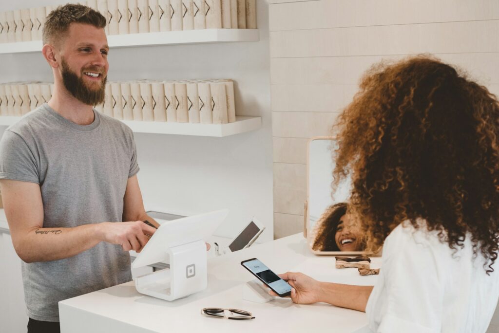 7 Vagas Abertas na Fais Consultoria, para São Bernardo e São Paulo man in grey crew-neck t-shirt smiling to woman on counter