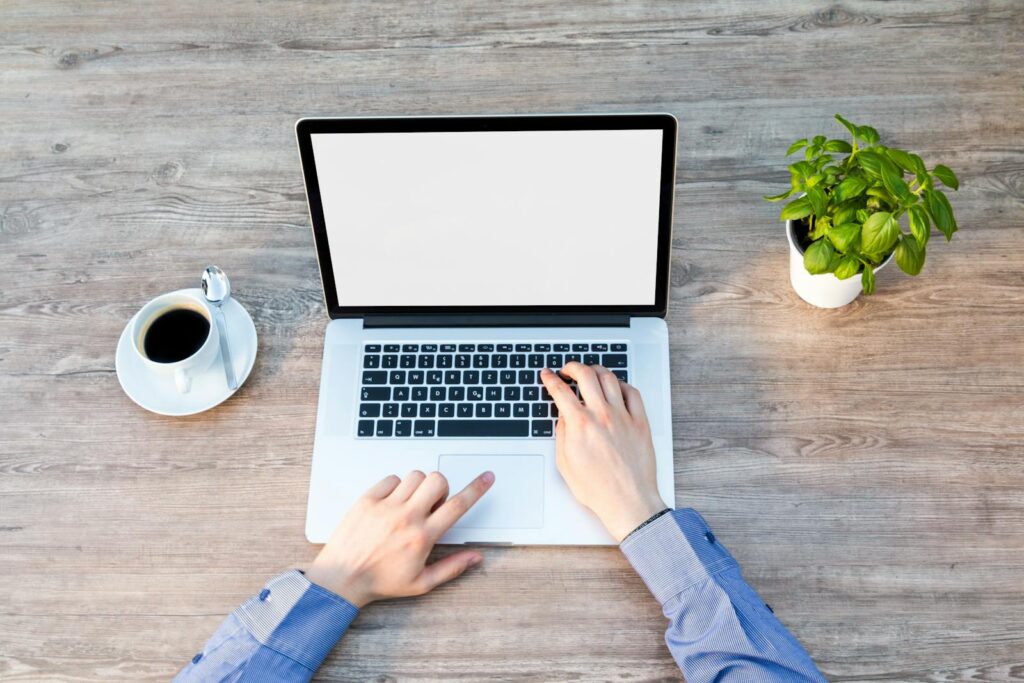 Vagas de Emprego Remoto A comforting workspace with a laptop, coffee cup, and potted plant on a wooden desk.