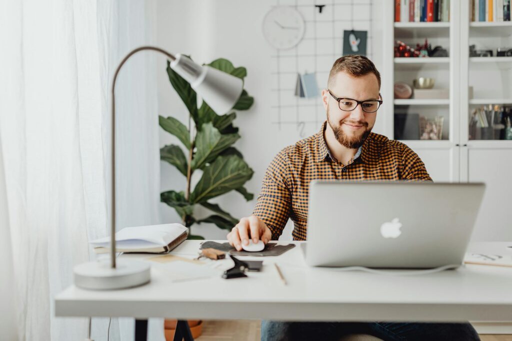 Vagas Administrativas Home Office Adult male working remotely in a stylish home office with a laptop, displaying a modern workspace.