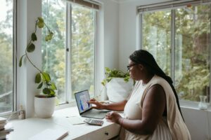 Vagas de Emprego na Hyperativa a woman sitting at a table with a laptop