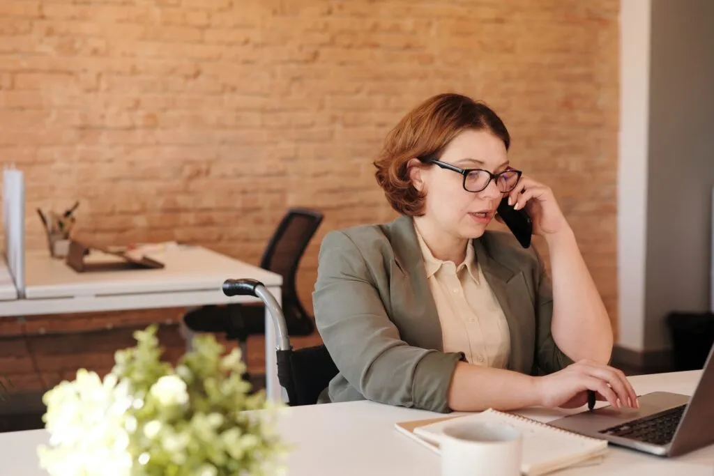 Home Office na Construtora Tenda 2023 Photo of Woman Talking Through Smartphone While Using Laptop